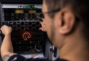 Profissional da Adentro manuseando equipamentos em rack de servidores.